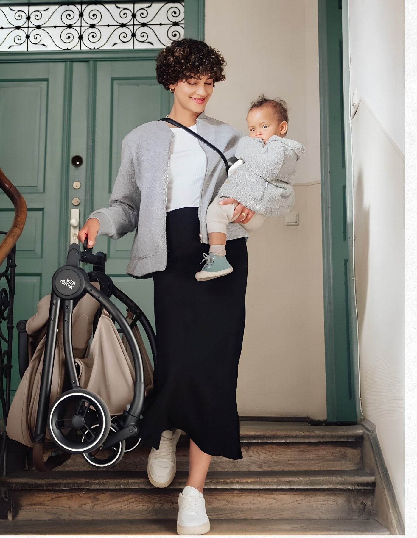 A parent carrying their baby and a Capital Kidz stroller