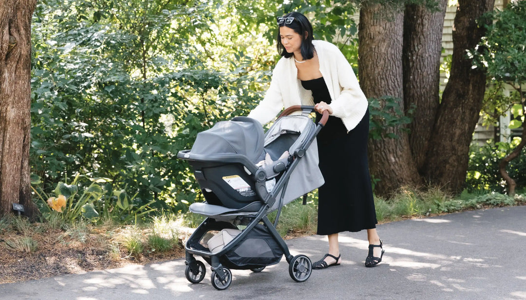 Caregiver with a Minu V3 stroller and an infant car seat attached using UPPAbaby Minu V3 adapters