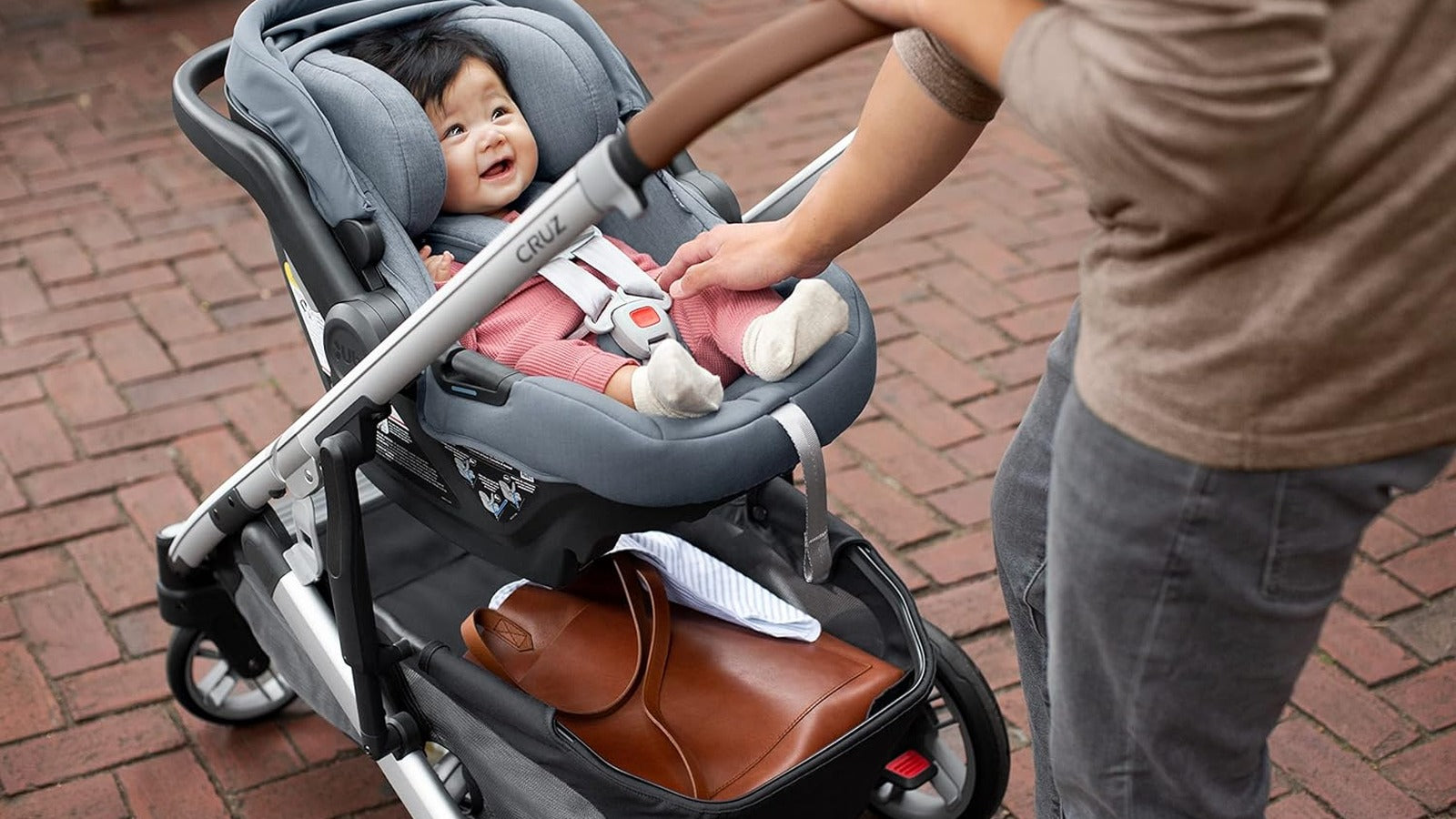 Parent securing baby in an infant car seat attached to a stroller