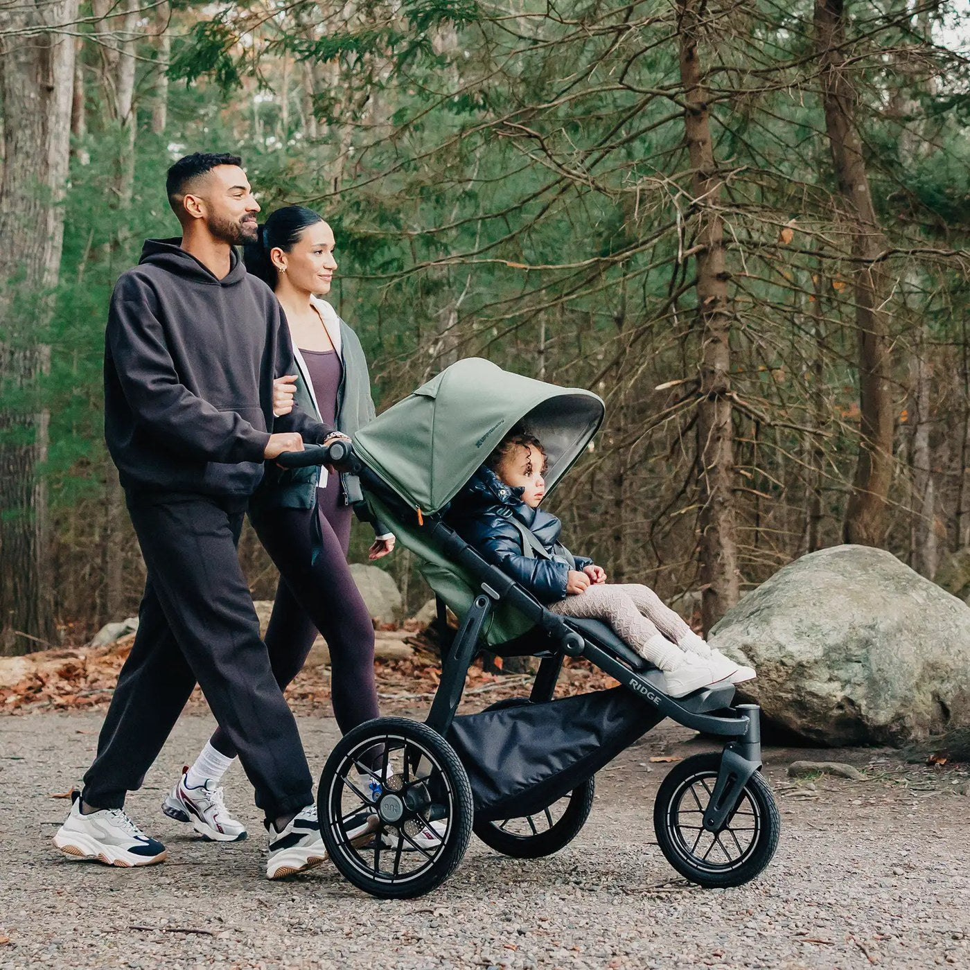 Family walking a wooded trail with an UPPAbaby all-terrain stroller